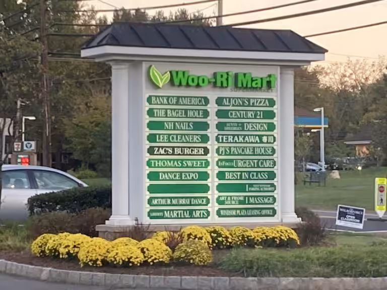 Shopping plaza directory sign in an area with plenty of trees and grass.