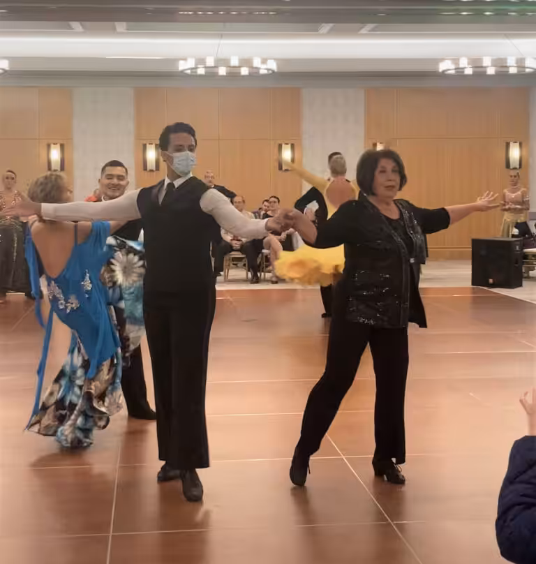 A couple performing a classic ballroom dance pose with other dancers in the background.