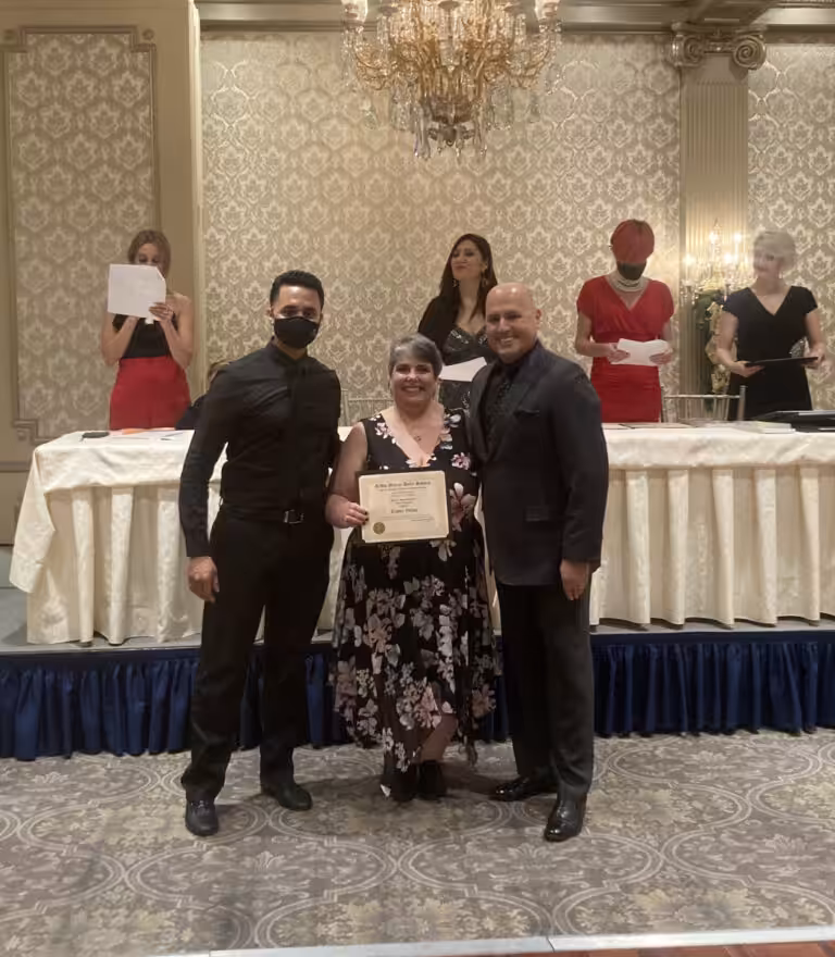 A woman shows her certificate in the company of two men at a formal event.