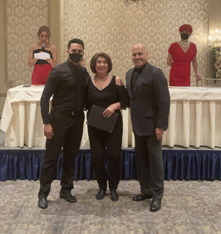 Three people posing for picture at a formal event.
