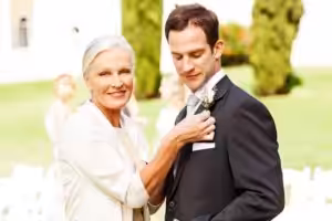A mother and a groom pose for a picture outdoors.