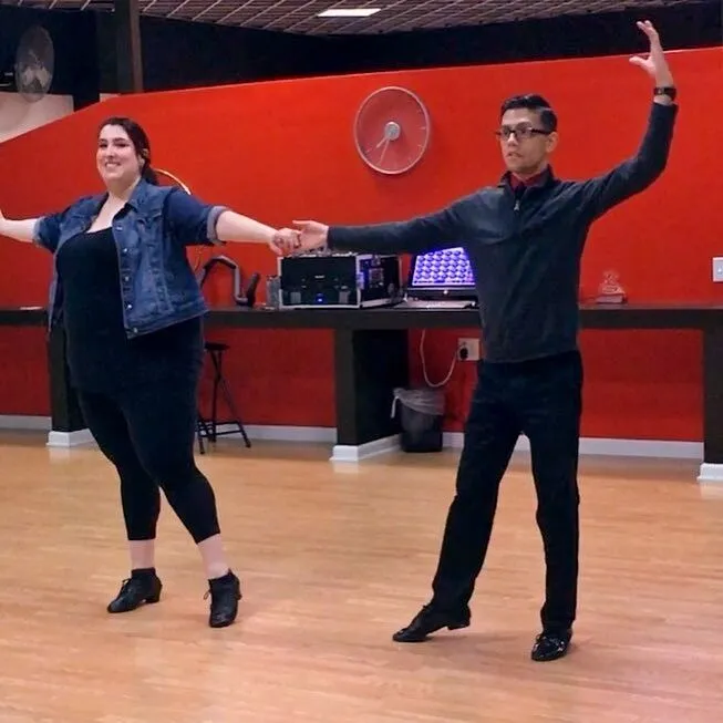 A couple finishing a dance move at a dance studio.