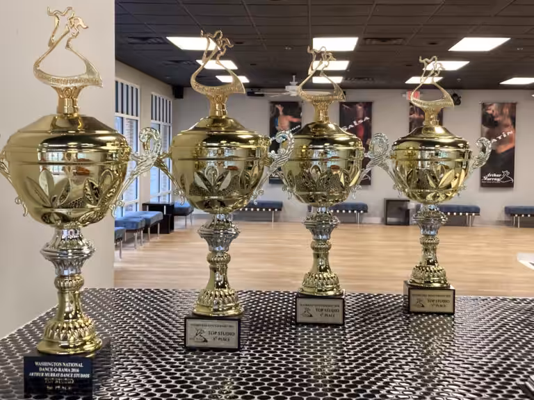 Four dance competition trophies on a table inside a dance studio.