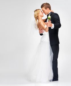 A bride and a groom dancing closely in front of a white background.