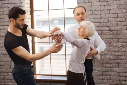 A senior couple enjoying a dance lesson with their instructor.